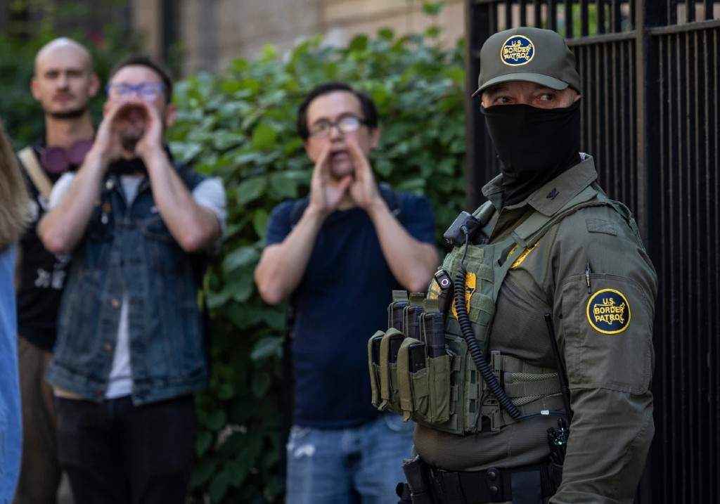 Pedestrians chant, “ICE go home!” as federal immigration agents stand on North Clark Street near West Oak Street in the River North neighborhood, Sunday, Sept. 28, 2025, in Chicago.