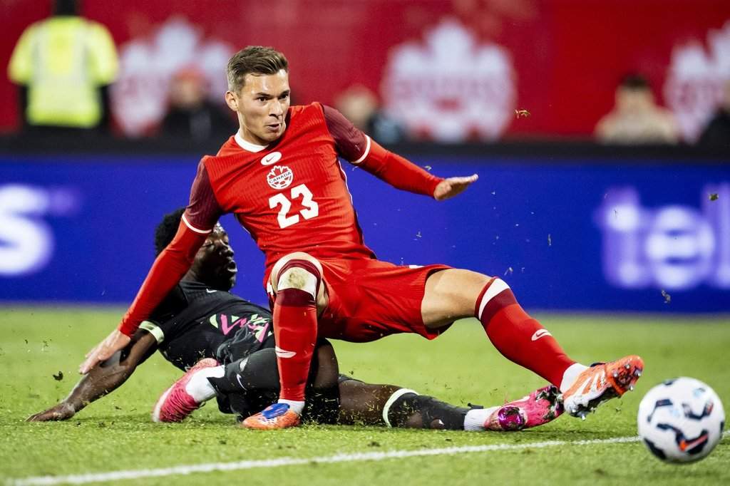 Australia's Nestory Irankunda (bottom) shoots past Canada's Niko Sigur (23) to score during second half international friendly soccer action in Montreal, on Friday, October 10, 2025. THE CANADIAN PRESS/Christopher Katsarov.