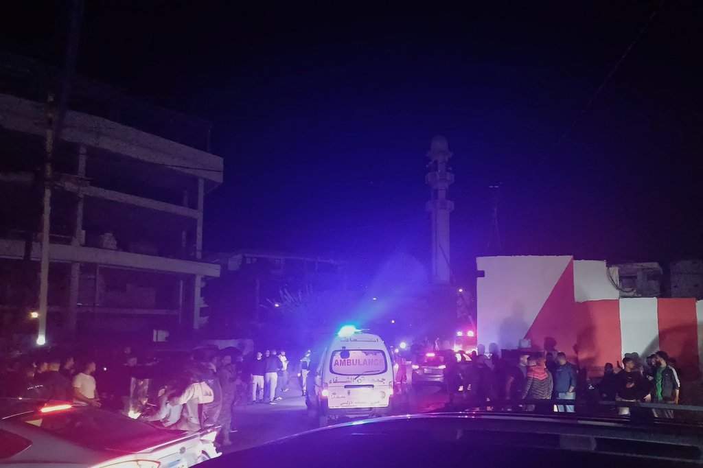 People gathering next of an ambulance as it enters the Ein el-Hilweh refugee camp in the southern port city of Sidon, Lebanon, Tuesday, Nov. 18, 2025. (AP Photo/Mohammed Zaatari).
