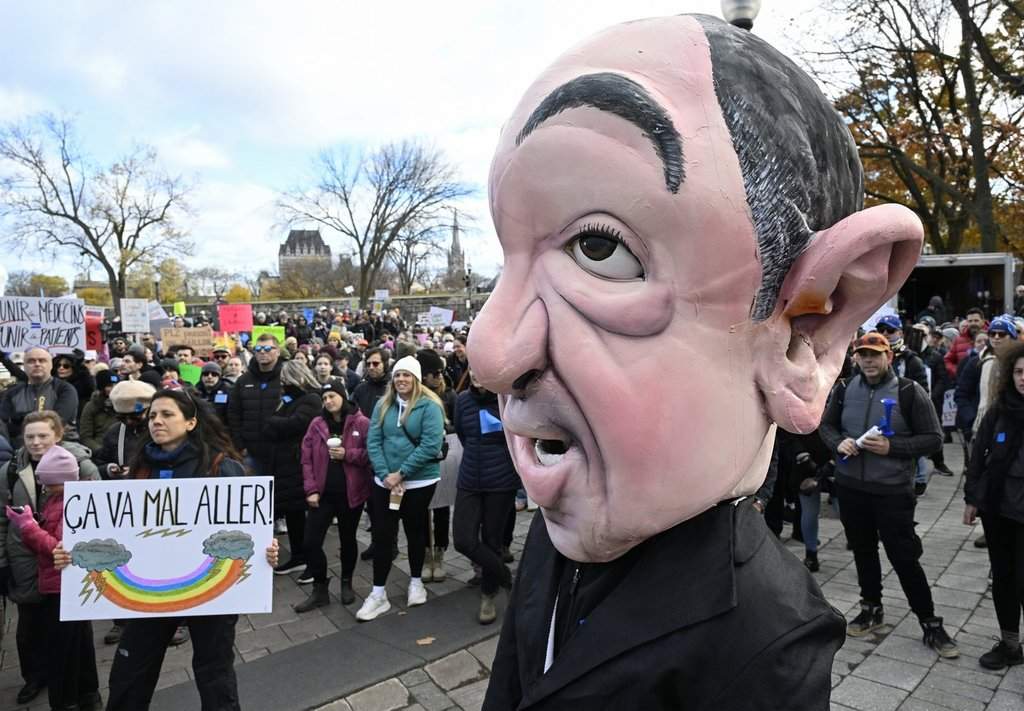 In front of the legislature in Quebec City, a giant puppet representing Quebec Health Minister Christian Dubé stands as people demonstrate against a law that changes how doctors are paid, Saturday, Nov. 1, 2025. THE CANADIAN PRESS/Jacques Boissinot