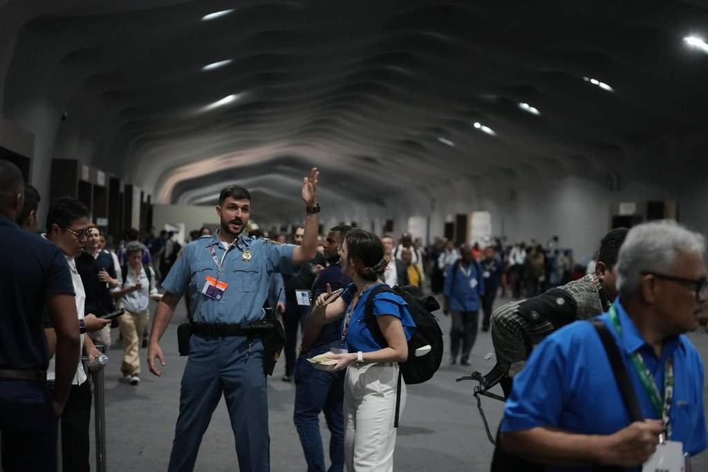 A security officer directs people to leave the venue for the COP30 U.N. Climate Summit, Thursday, Nov. 20, 2025, in Belem, Brazil. (AP Photo/Fernando Llano).