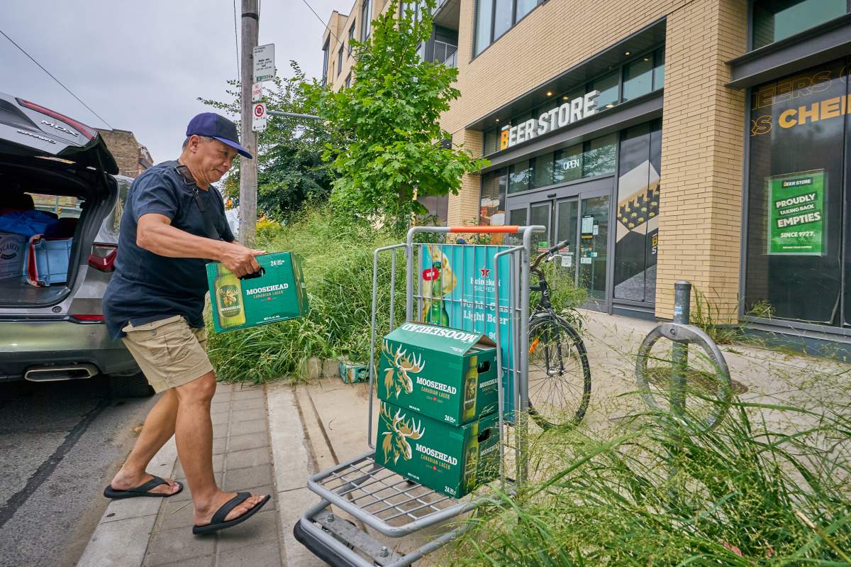 Shoppers bring boxes of empty beer bottles to a Beer Store on Gerrard Street in Toronto’s east end that is scheduled to close this fall, on Tuesday, August 19, 2025. 