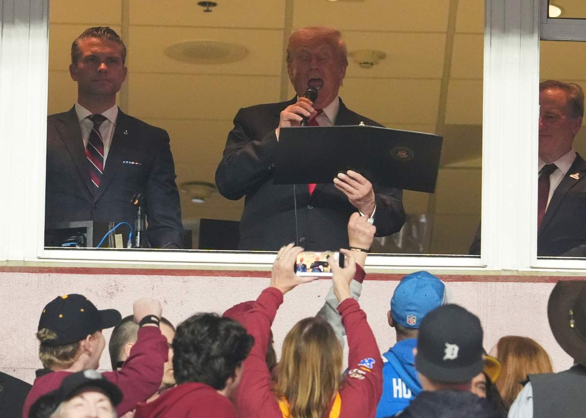 President Donald Trump delivers the Oath of Enlistment alongside Defense Secretary Pete Hegseth, left, during an NFL football game between the Washington Commanders and the Detroit Lions at Northwest Stadium in Landover, Md., Sunday, Nov. 9, 2025.