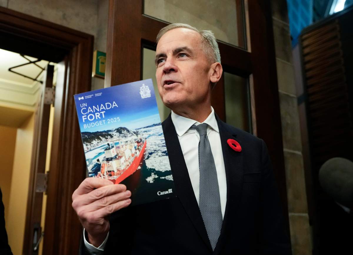 Prime Minister Mark Carney holds up a copy of the budget as he and Minister of Finance and National Revenue Francois-Philippe Champagne, not shown, make their way to the House of Commons for the tabling of the federal budget on Parliament Hill in Ottawa, on Tuesday, Nov. 4, 2025.
