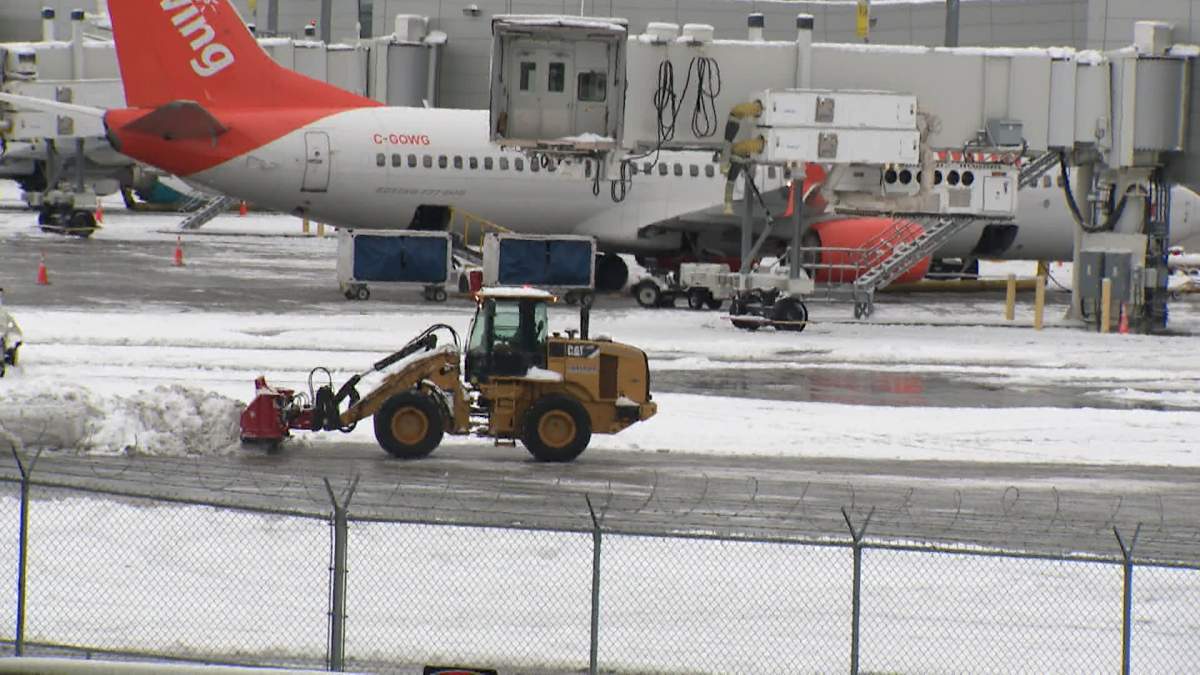 A front end loader clears snow from the tarmac at Calgary International Airport on Monday as crews scramble to clear a backlog of dozens of flights that were cancelled or delayed because of the snow.