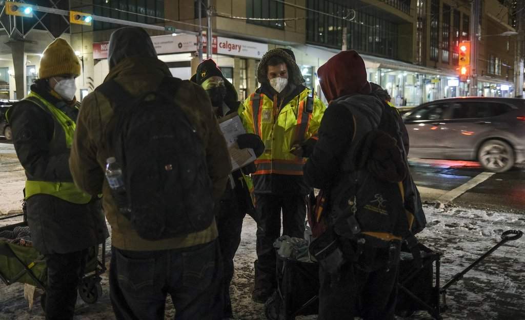 BeTheChangeYYC uutreach volunteer Chaz Smith, second right, offers help to the homeless on a -20 C night in Calgary on Tuesday, Dec. 14, 2021. 