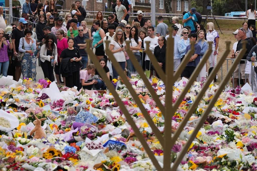 A menorah stands by a floral tribute honouring the victims of the Dec. 14 attack on a Hanukkah celebration at Bondi Beach in Sydney, Australia. (AP Photo/Mark Baker).