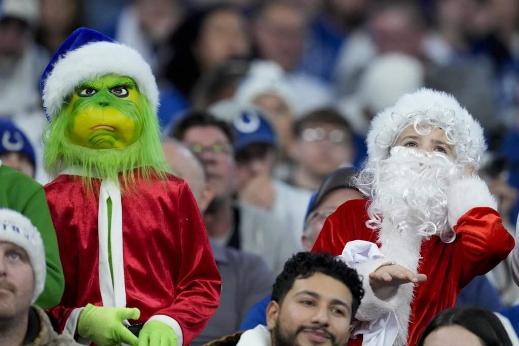Fans dressed as the Grinch, left, and Santa Claus, right, watch during the second half of an NFL football game between the Indianapolis Colts and the Tennessee Titans, Sunday, Dec. 22, 2024, in Indianapolis.