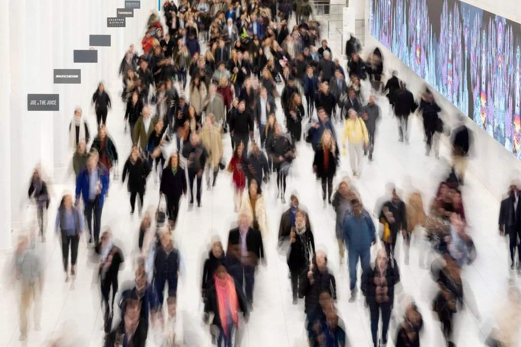FILE - Commuters walk along a corridor in the World Trade Center, Monday, Nov. 18, 2019 in New York. (AP Photo/Mark Lennihan, File).