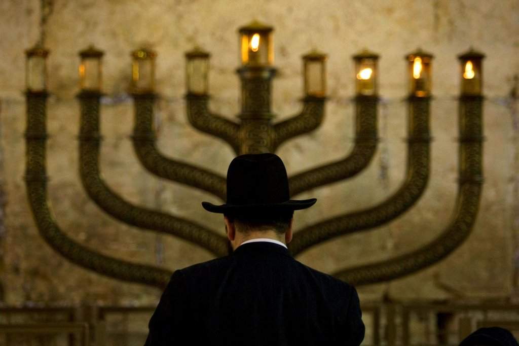 FILE - An Ultra-Orthodox Jewish man stands in front of a menorah on the third eve of Hanukkah, at the Western Wall, Judaism's holiest site in Jerusalem's old city, Sunday, Dec. 13, 2009. (AP Photo/Sebastian Scheiner, File).