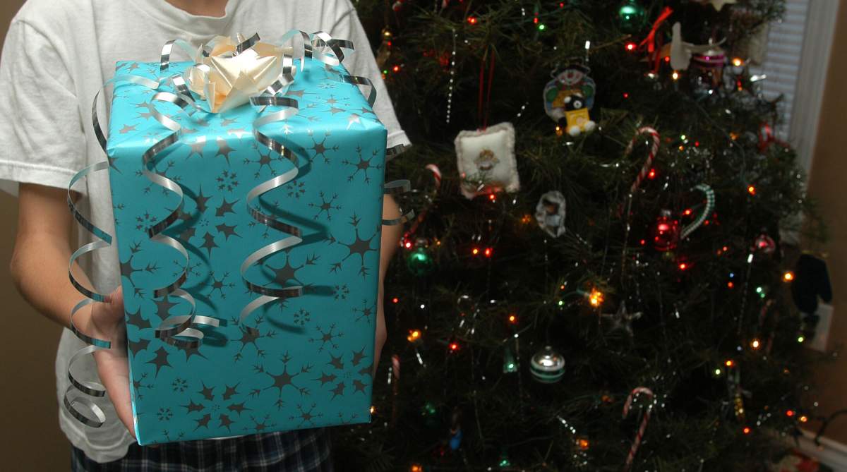 Photo of a holiday gift next to a Christmas tree