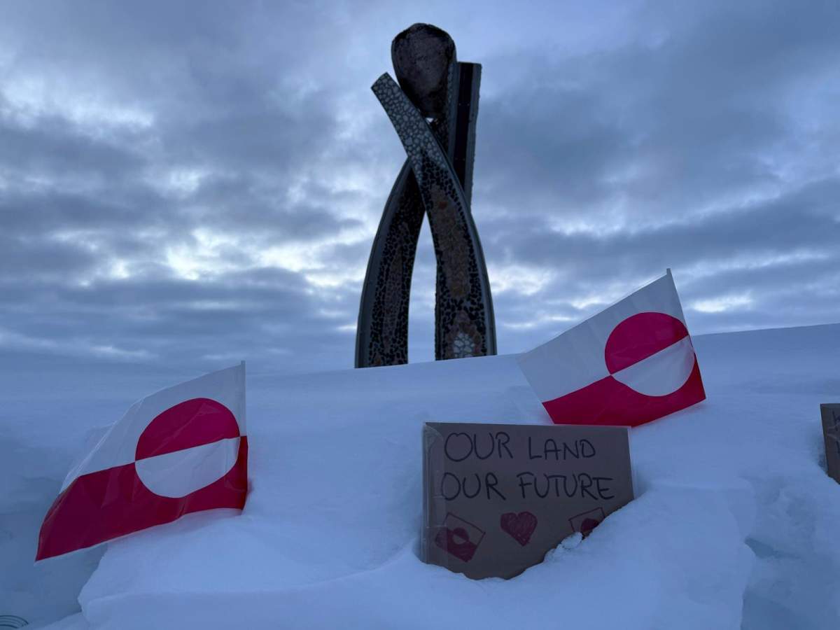 Two Greenland flags and a sign that reads 'Our land, Our future' are seen in front of the Inussuk statue, a sculpture marking the start of Self Governance, during a visit by U.S. Vice-President JD Vance in Nuuk Greenland, on March 28, 2025. (AP Photo/ Philip Crowther)