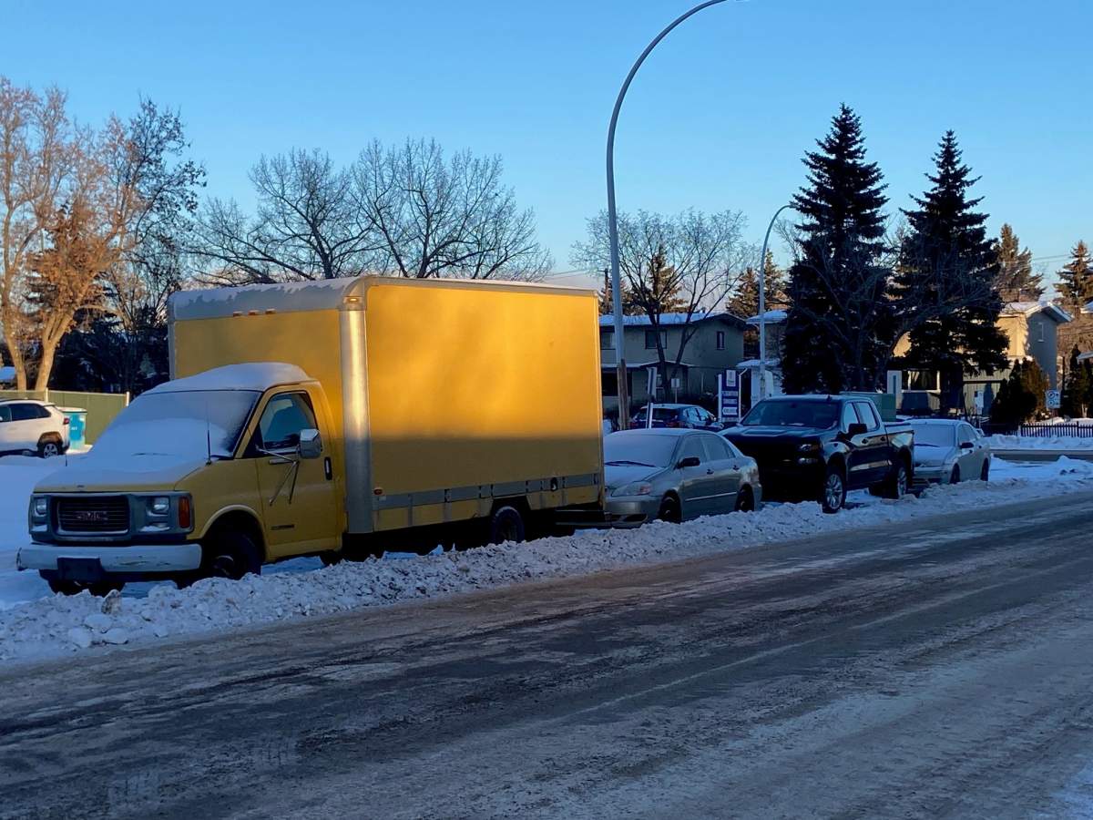 Vehicles that did not move off an Edmonton street and had a windrow plowed around them during a seasonal parking ban in December 2025.