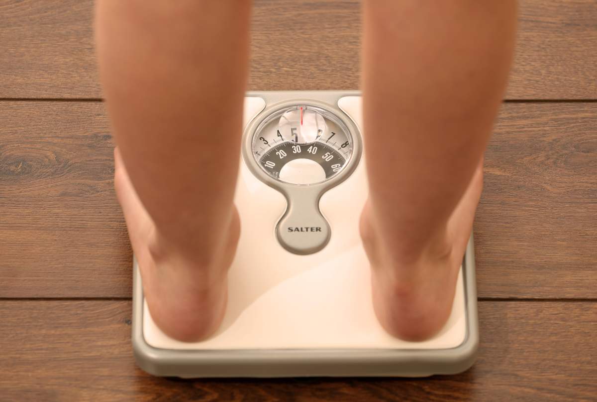 A person stands on a weighing scale.