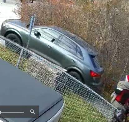 A grey Audi squeezes through a pedestrian path during a Santa Claus parade.