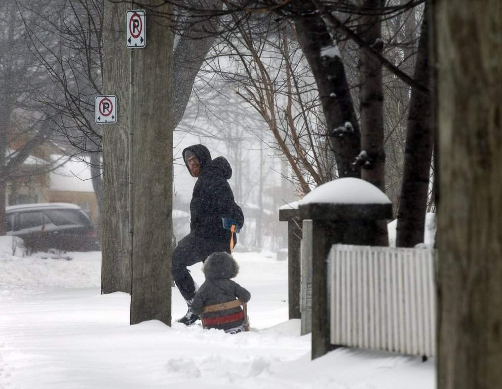 A resident takes advantage of a lull to take their child for a sleigh ride in St. John's on Friday, March 8, 2024. THE CANADIAN PRESS/Paul Daly.