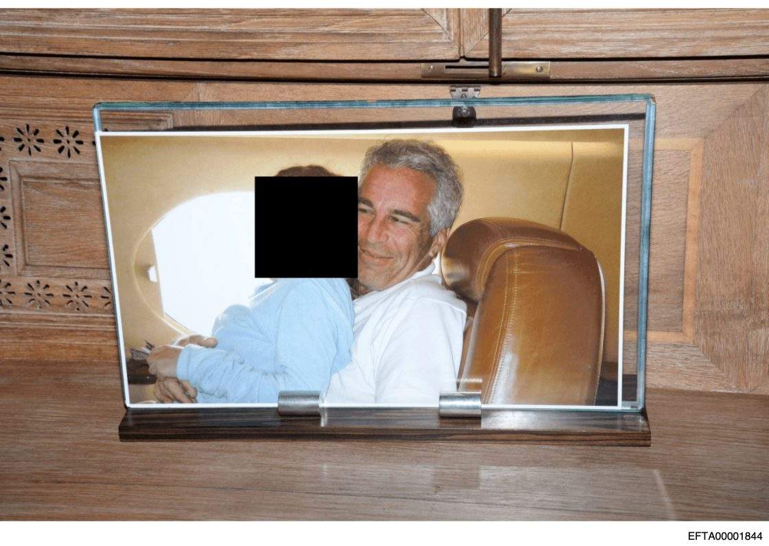 This redacted photo released by the U.S. Department of Justice shows a framed photograph of Jeffrey Epstein with a person on his lap.