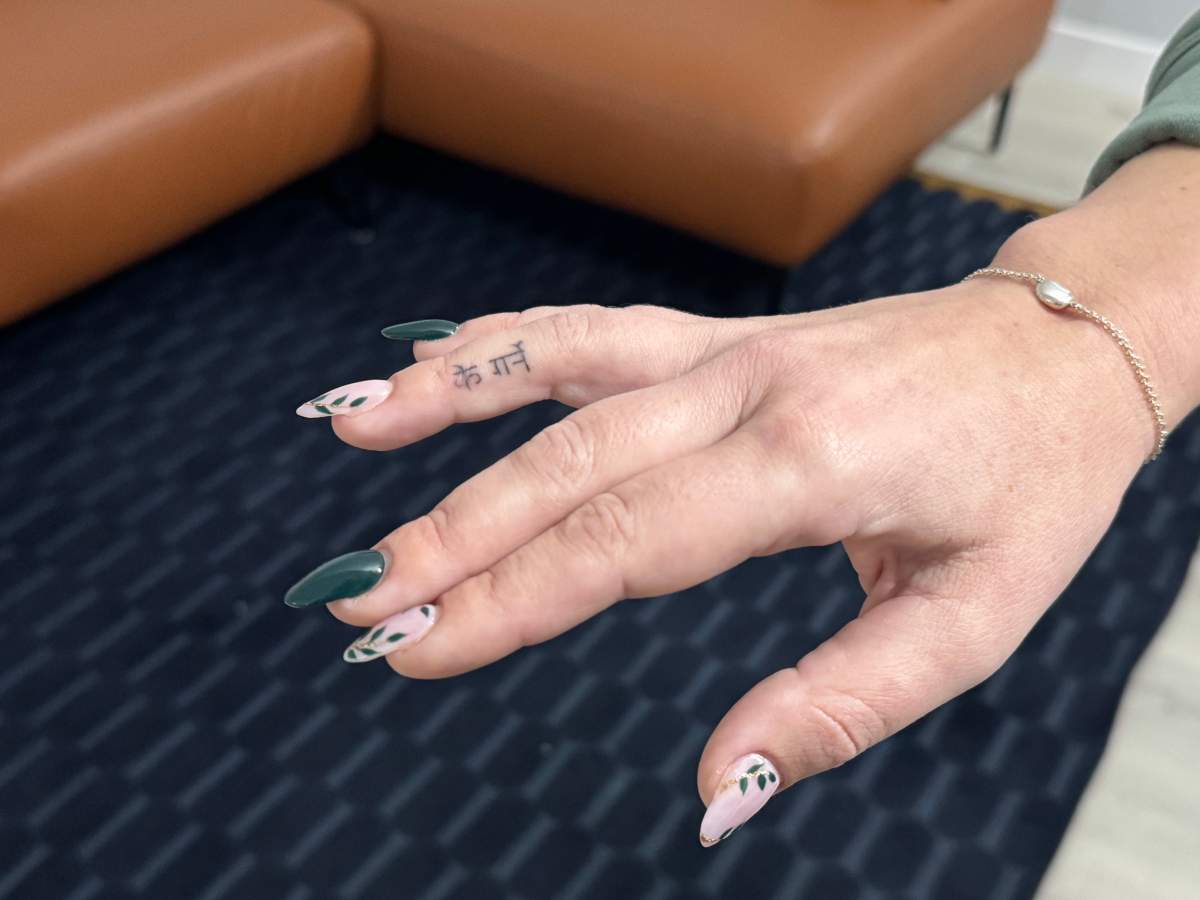 A small tattoo on Tracy Lima’s right hand spells out the Nepali phrase “ke garne.”