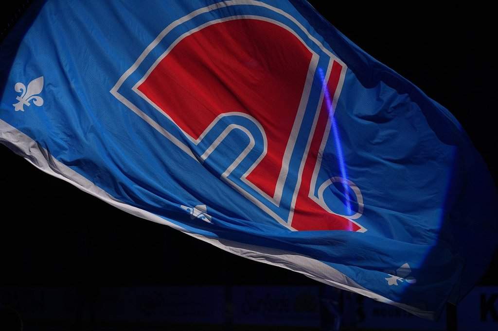 The logo of the former NHL team the Quebec Nordiques adorns a flag used during a pre-game ceremony by the Nordiques' successor, the Colorado Avalanche, in the first period of an NHL hockey game Thursday, Oct. 23, 2025, in Denver. (AP Photo/David Zalubowski).