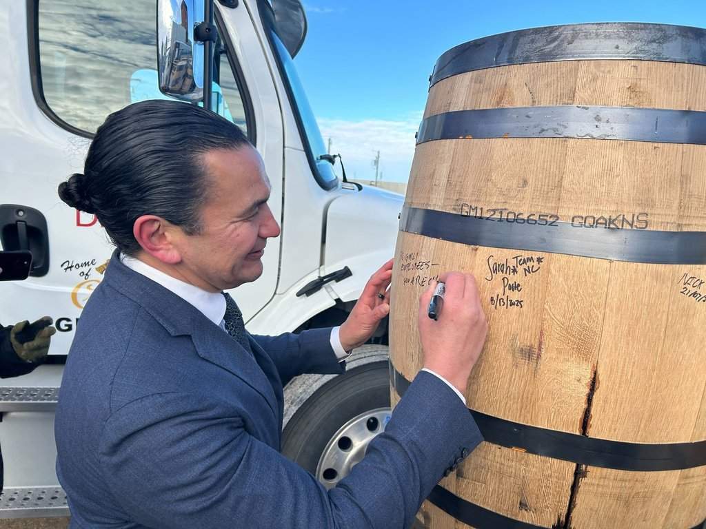 Manitoba Premier Wab Kinew signs barrels outside the Diageo plant where Crown Royal whisky is produced, in Gimli, Man., on Tuesday, Jan. 13, 2026. Kinew is calling on Ontario Premier Doug Ford to cancel a planned boycott of the whisky. THE CANADIAN PRESS/Steve Lambert.