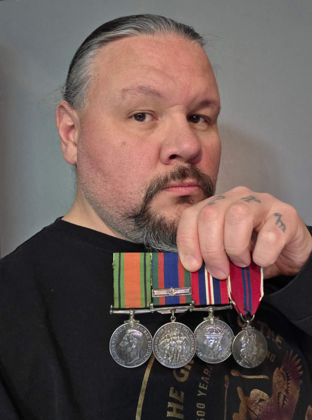 Military historian, John Brady McDonald, holding medals last week that he believed belonged to a veteran with family in Winnipeg