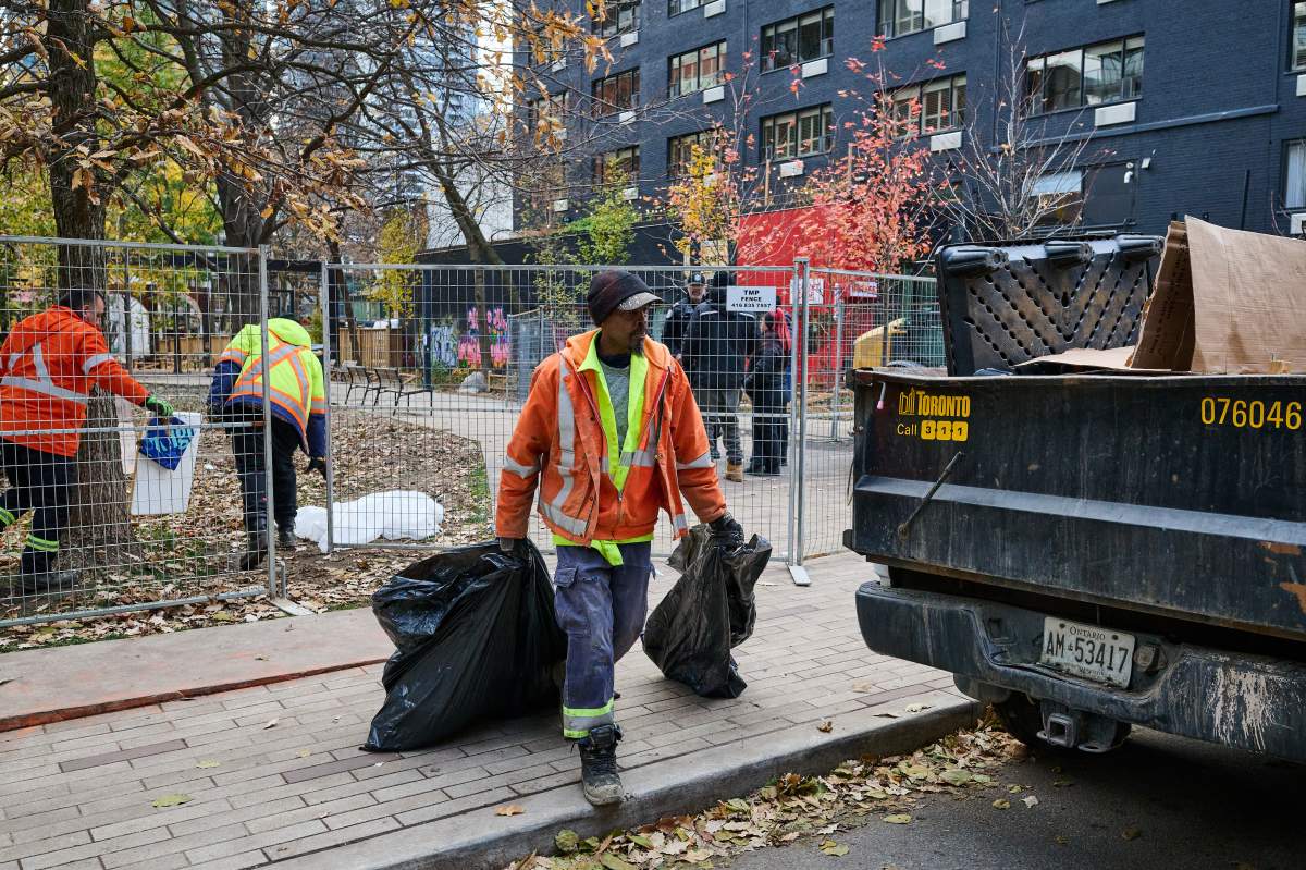 Workers clear an encampment at George Hislop park, in Toronto, on Monday, Nov. 17, 2025.