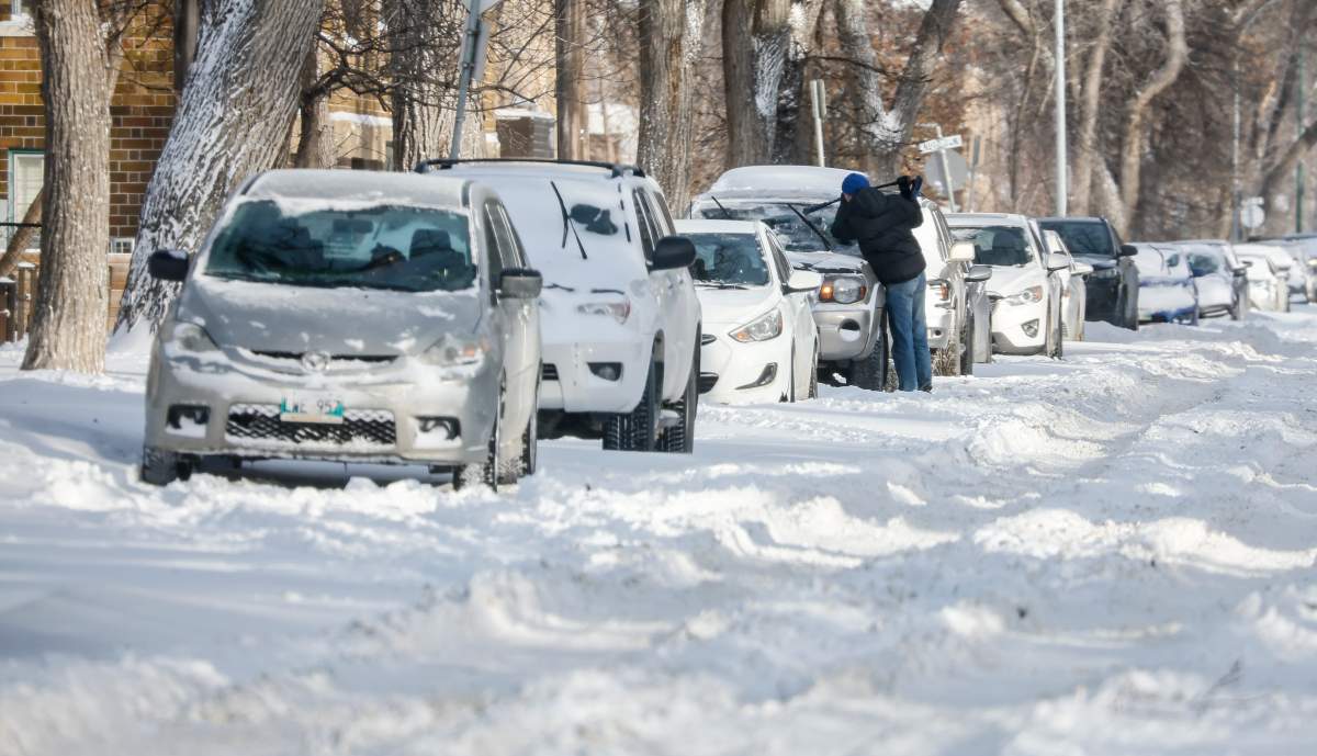 A person scrapes their windshield after an overnight snow storm, in Winnipeg, Thursday, Dec. 18, 2025. 