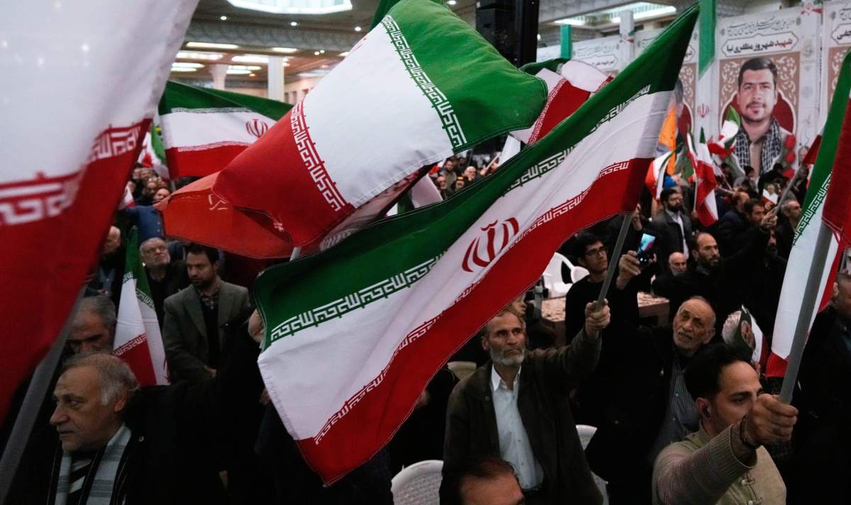 People wave national flags during a ceremony commemorating the death anniversary of the late commander of the Iran's Revolutionary Guard expeditionary Quds Force, Gen. Qassem Soleimani, who was killed in a U.S. drone attack in 2020 in Iraq, at the Imam Khomeini grand mosque in Tehran, Iran, Thursday, Jan. 1, 2026. (AP Photo/Vahid Salemi).