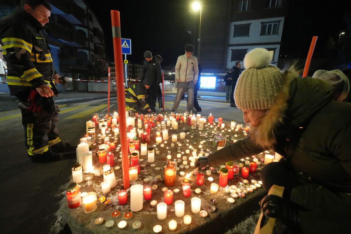 People lay candles and flowers near the Le Constellation bar, where a devastating fire left dead and injured during the New Year’s celebrations in Crans-Montana, Swiss Alps, Switzerland, Thursday, Jan. 1, 2026.