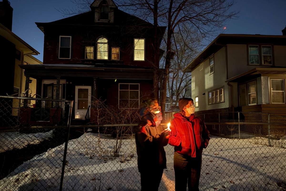 Two attendees stand during a vigil near where an Immigration and Customs Enforcement officer shot and killed a woman in Minneapolis, Wednesday, Jan. 7, 2026.
