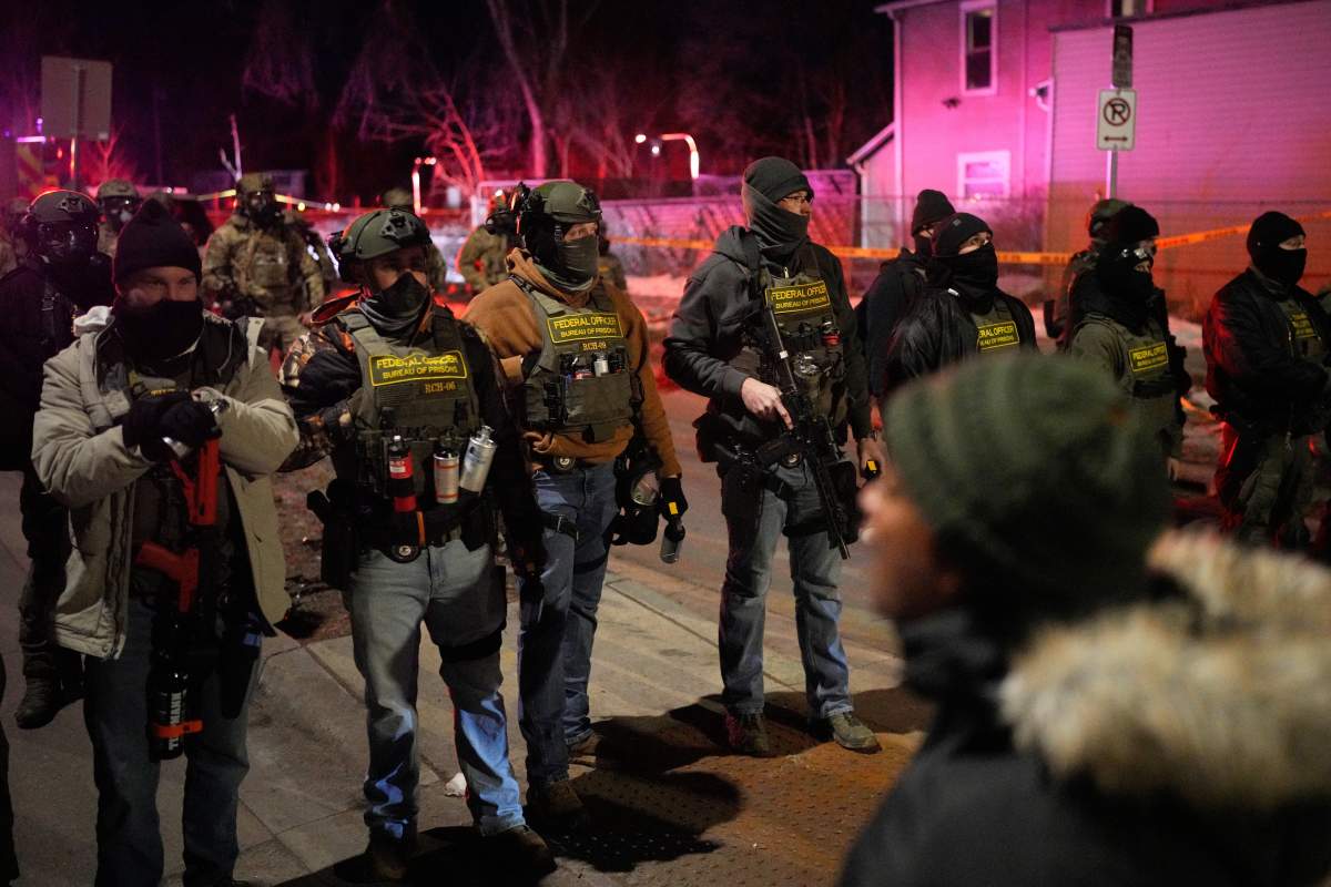 Federal law enforcement officers stand against protesters after a shooting on Wednesday, Jan. 14, 2026, in Minneapolis.