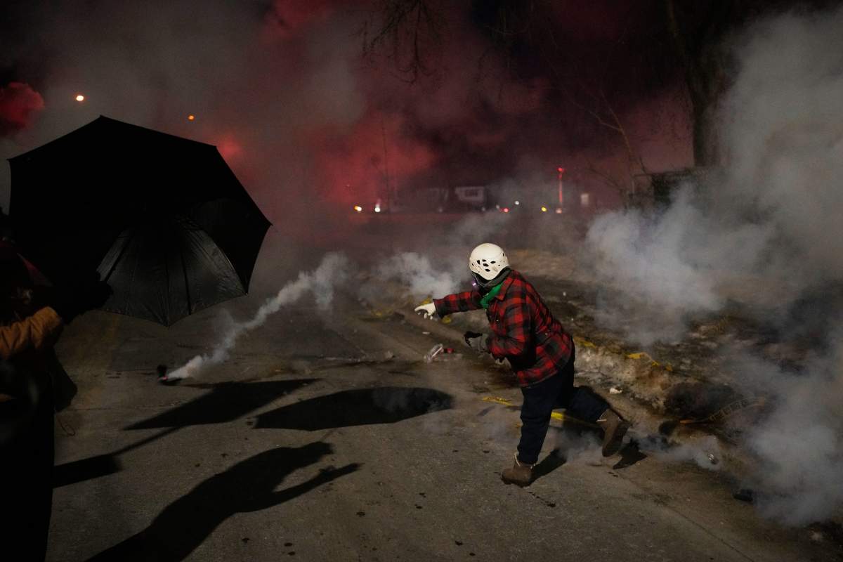 A protester throws back a tear gas canister during a protest after a shooting on Wednesday, Jan. 14, 2026, in Minneapolis.