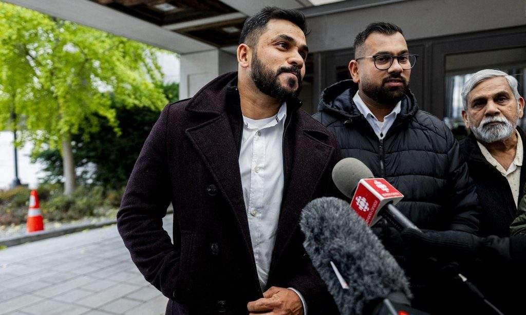 Dhanushka Wickramasinghe, centre, looks on towards Immigration Lawyer and family representative Ronalee Carey as she speaks to reporters outside of the Ottawa Courthouse in Ottawa, on Thursday, Nov. 6, 2025. Wickramasinghe is the sole survivor of a mass stabbing incident in Ottawa’s Barrhaven region that took the lives of his four children, his wife and a family friend. THE CANADIAN PRESS/Spencer Colby.