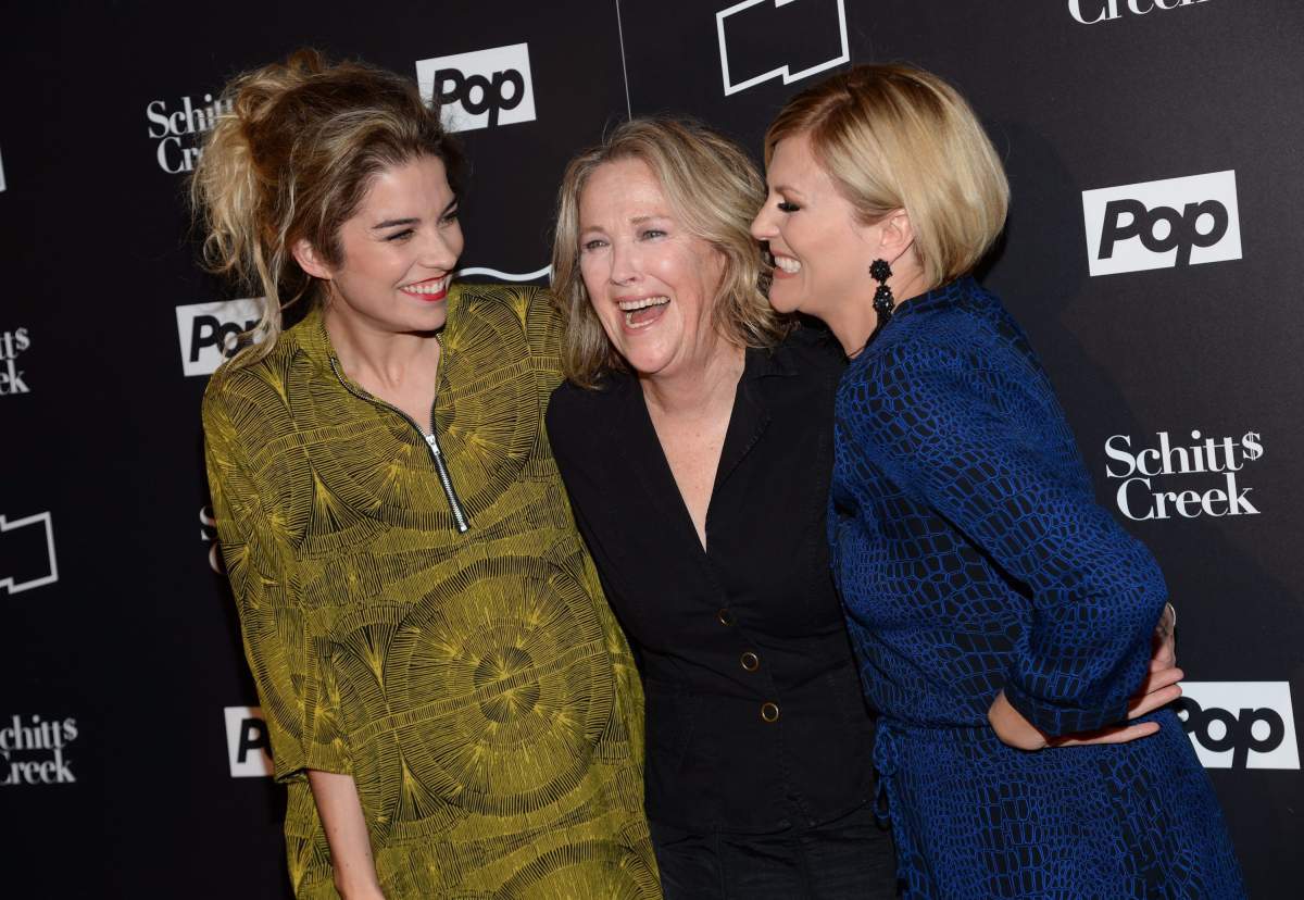 Catherine O'Hara laughs in between two fellow actors from Schitt's Creek