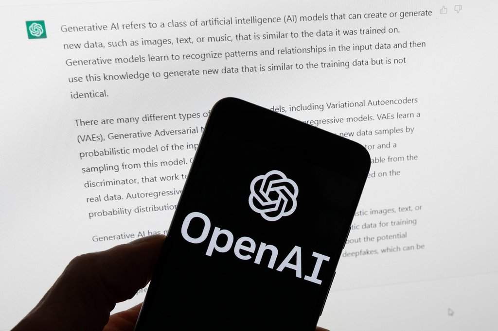 FILE - The OpenAI logo is displayed on a mobile phone in front of a computer screen with output from ChatGPT, March 21, 2023, in Boston. (AP Photo/Michael Dwyer, File).