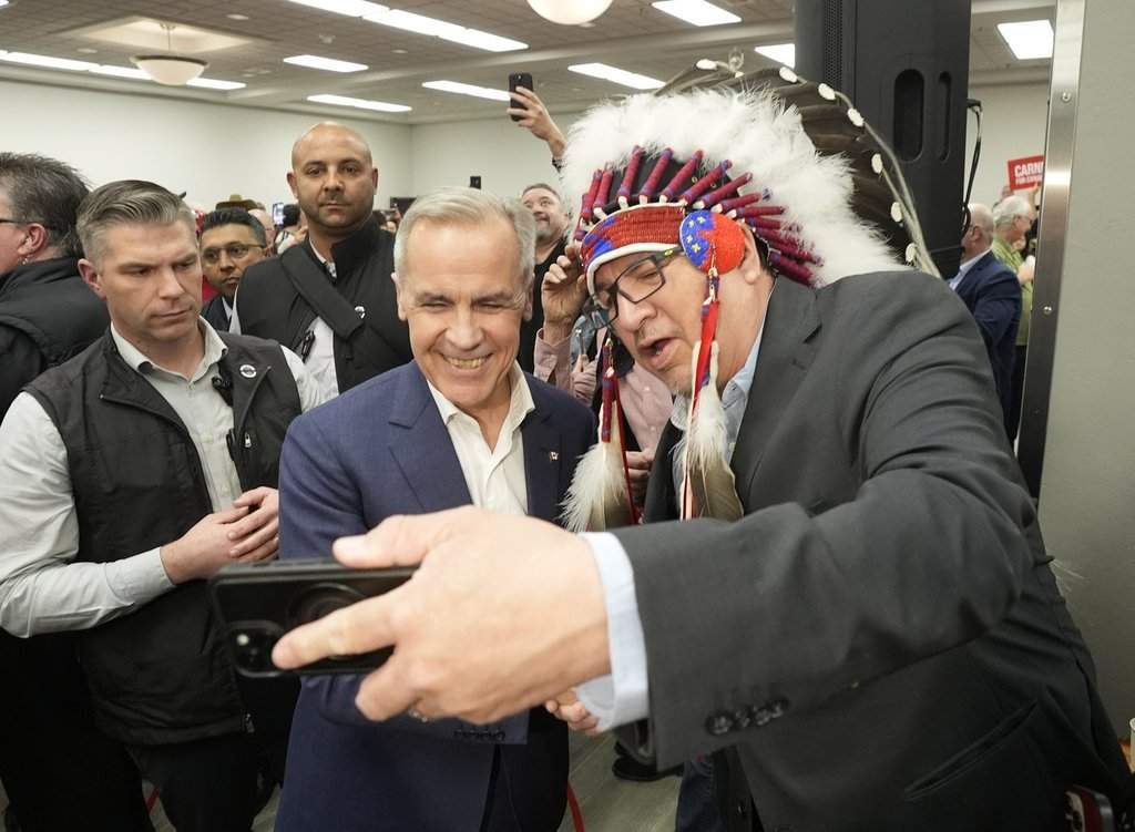 Pimicikamak Cree Nation Chief David Monias gets a selfie with Mark Carney at a federal election campaign rally in Winnipeg, Tuesday, April 1, 2025. THE CANADIAN PRESS/Adrian Wyld.