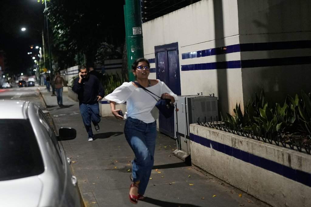 Pedestrians run after explosions and low-flying aircraft were heard in Caracas, Venezuela, Saturday, Jan. 3, 2026. (AP Photo/Matias Delacroix)