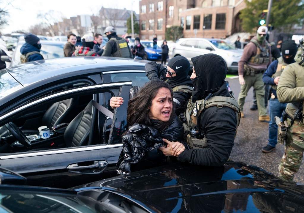 ICE agents detain a woman after pulling her from a car on January 13, 2026 in Minneapolis, Minnesota.