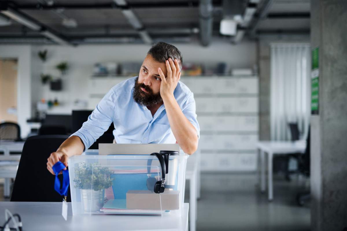 A disappointed tech worker clears his desk after receiving a layoff notice from his employer.
