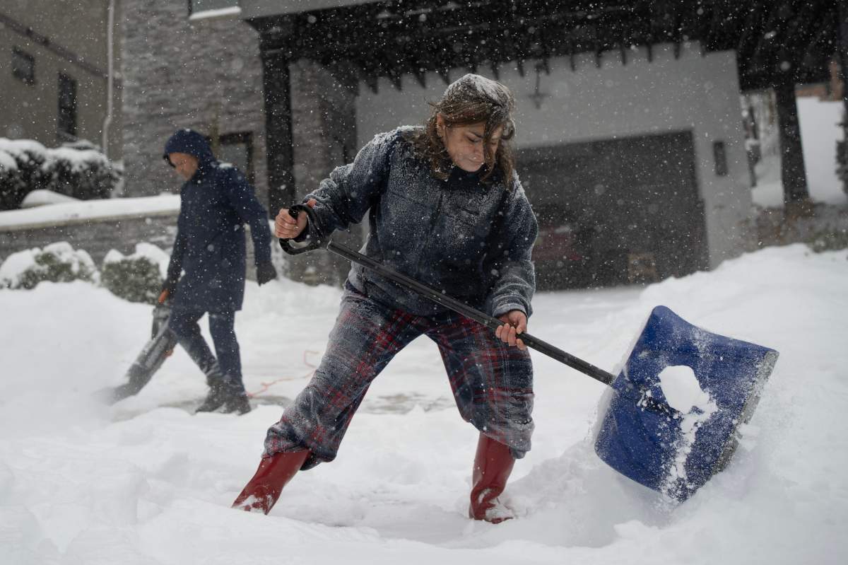 Priyanka Gogia, right, shovels and Sunit Gogia, left, uses a blower, to clear snow from their driveway during a winter storm, Sunday, Jan. 25, 2026, in Cincinnati.