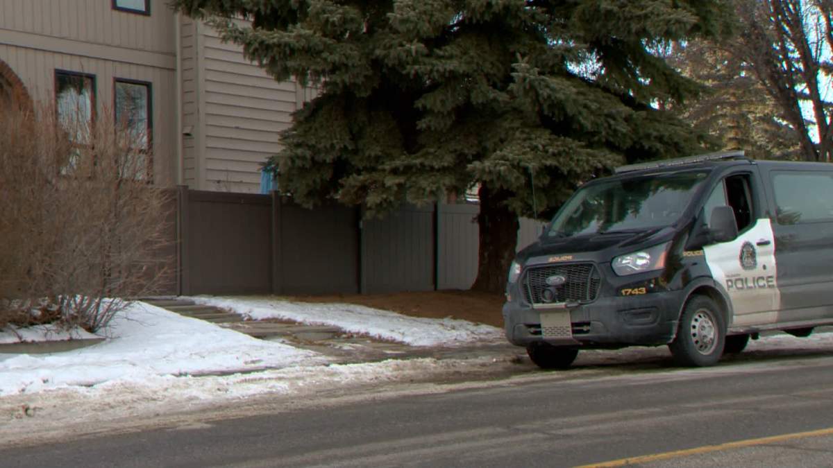 A Calgary police van is seen outside a house in Canyon Meadows on Friday where a day earlier officers were called out to the discovery of the body of a woman in her 80s, which is now being investigated as a domestic homicide.