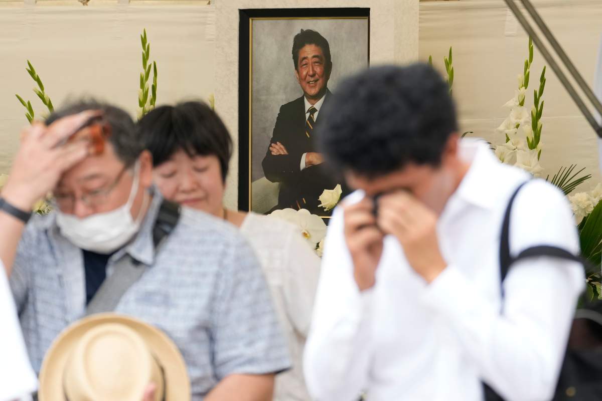 FILE-- People react after offering flowers and prayers for Japan's former Prime Minister Shinzo Abe at Zojoji temple Saturday, July 8, 2023, in Tokyo. Japan marked the first anniversary of the death of Abe who was shot while giving an outdoor campaign speech. 