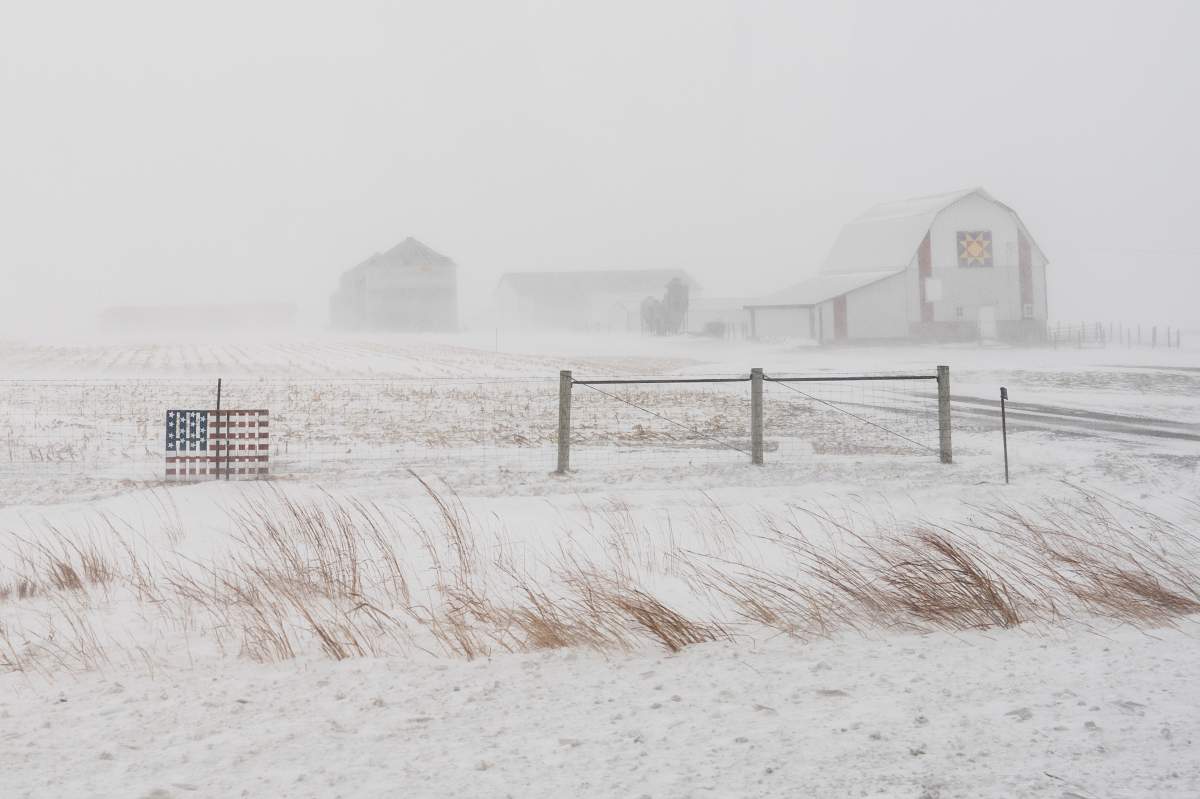 A U.S flag is seen on a field of grass as winter storm hits.