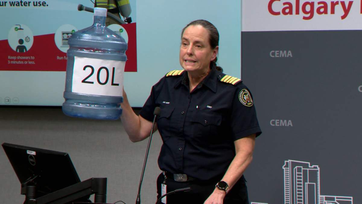 The head of Calgary's Emergency Management Agency, holds up a large water bottle, as she renewed a plea for city residents to cut back on their water use.