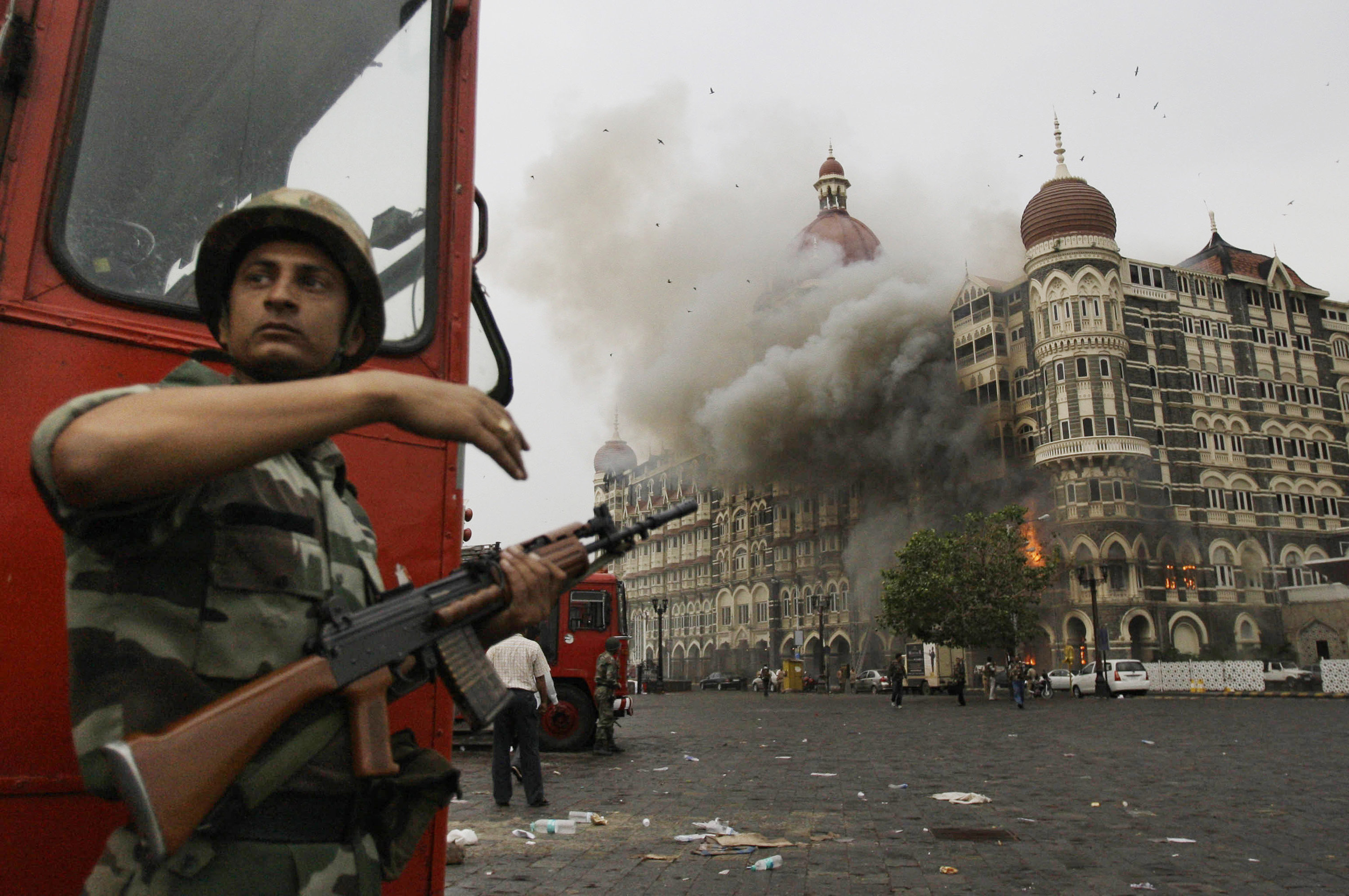 Indian soldier takes cover as the Taj Mahal hotel burns during gun battle between with militants, Mumbai, Nov. 29, 2008. (AP Photo/David Guttenfelder).