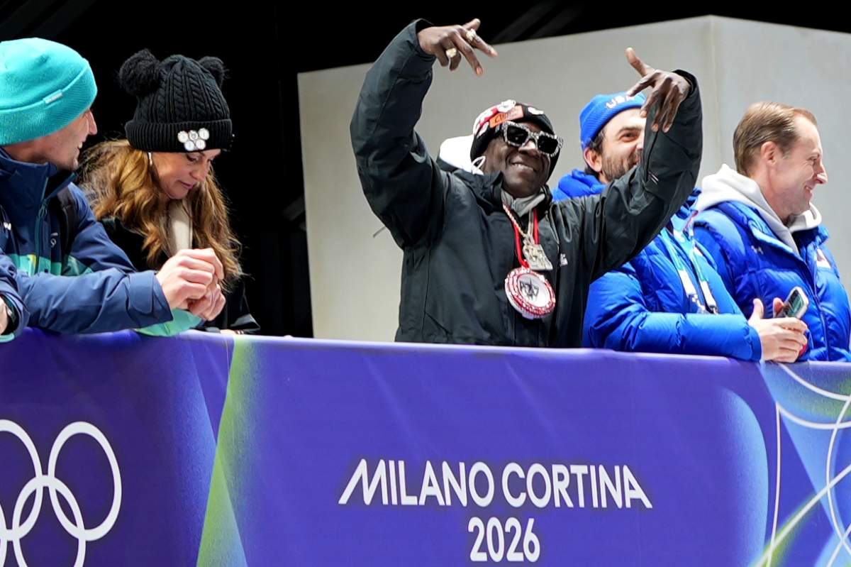American rapper Flavor Flav, center, attends the skeleton mixed team competition at the 2026 Winter Olympics, in Cortina d'Ampezzo, Italy, Sunday, Feb. 15, 2026.