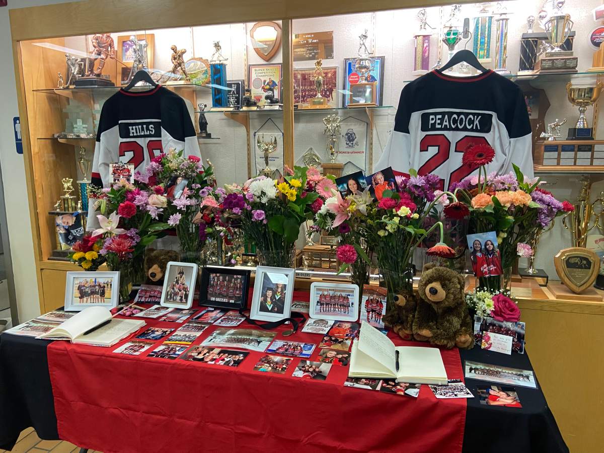 A memorial containing the jerseys and hockey cards of Jasper Bearcats players Danica Hills and Kayla Peacock, who died in a collision while going home to Hinton, Alta. on Monday, Feb. 23, 2026.