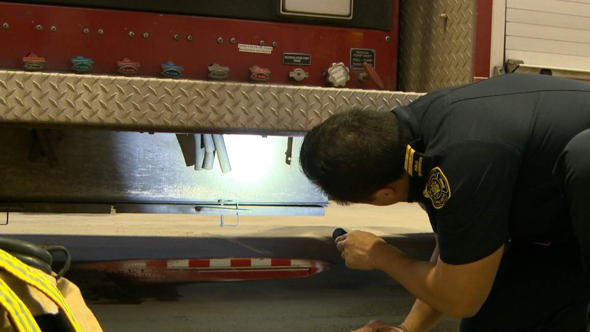 A member of the Calgary Fire Department checks the undercarriage of a fire truck for signs of corrosion.