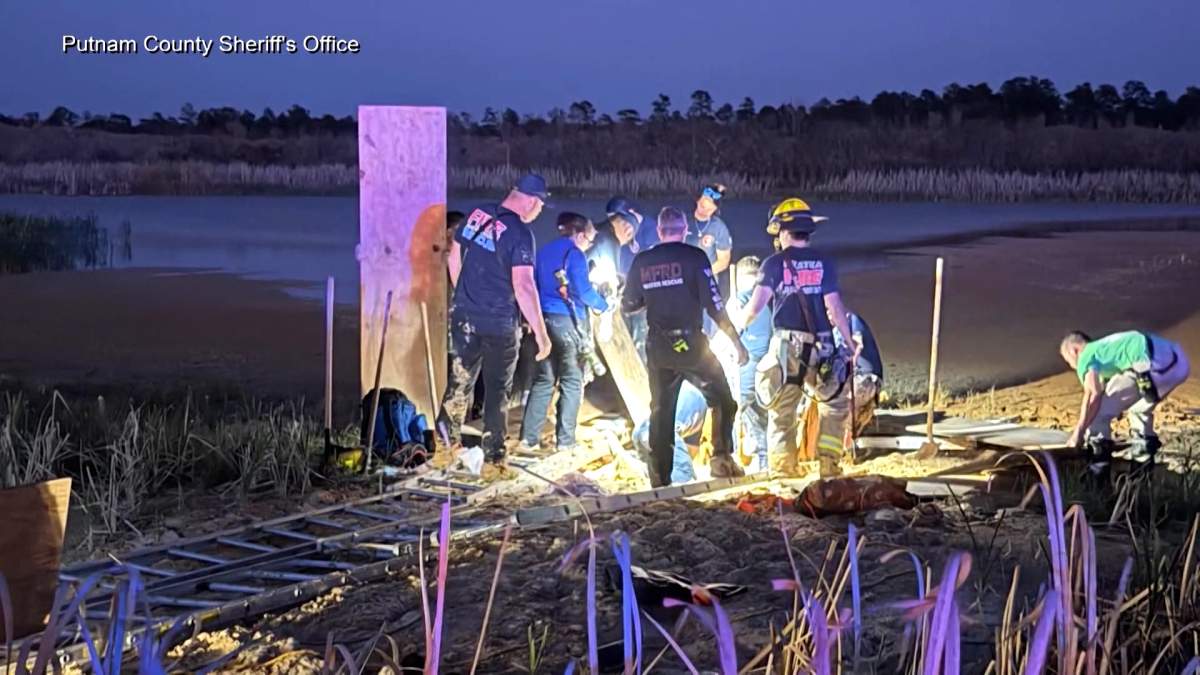 Rescue staff work to remove a Florida man who became stuck in a pit of mud-like quicksand.