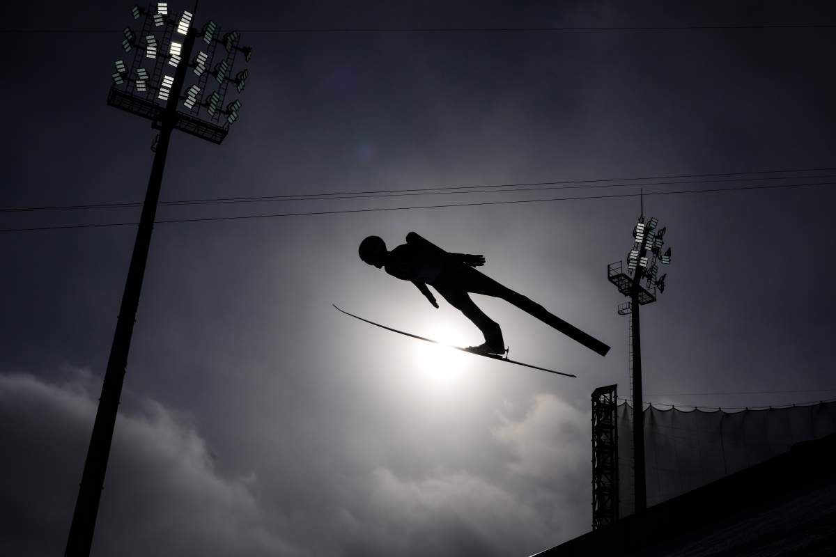A ski jumper soars through the air in silhouette